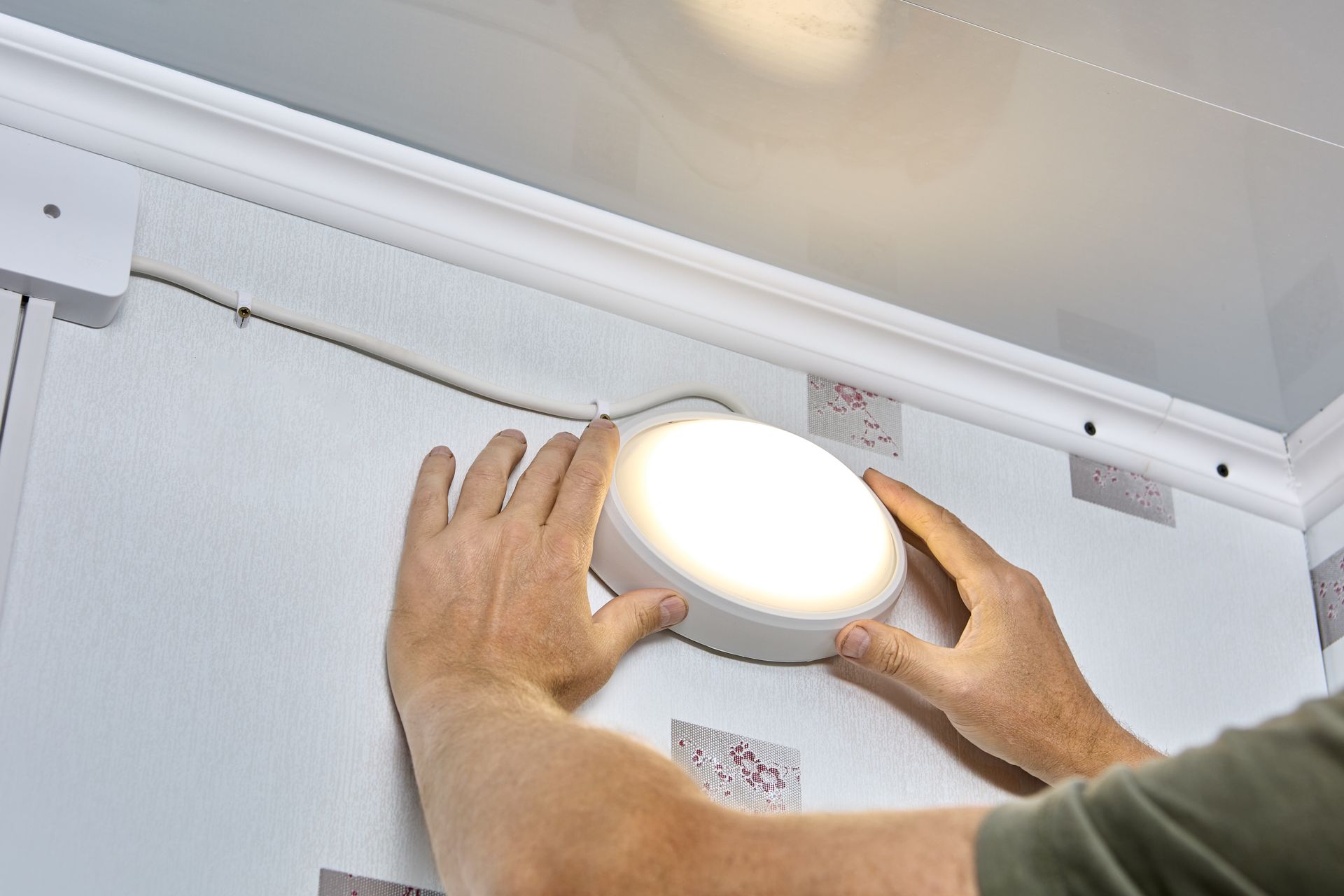 A person is installing a light on a wall.