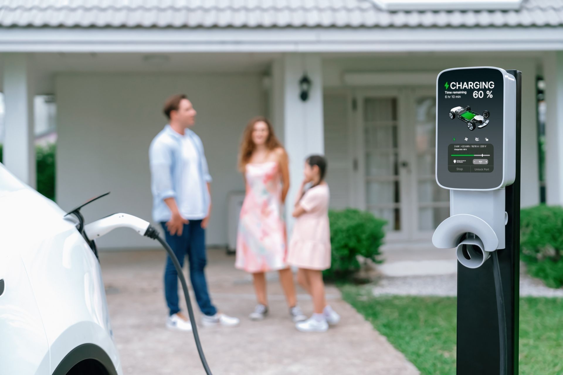 A family is standing in front of a house while a car is being charged.