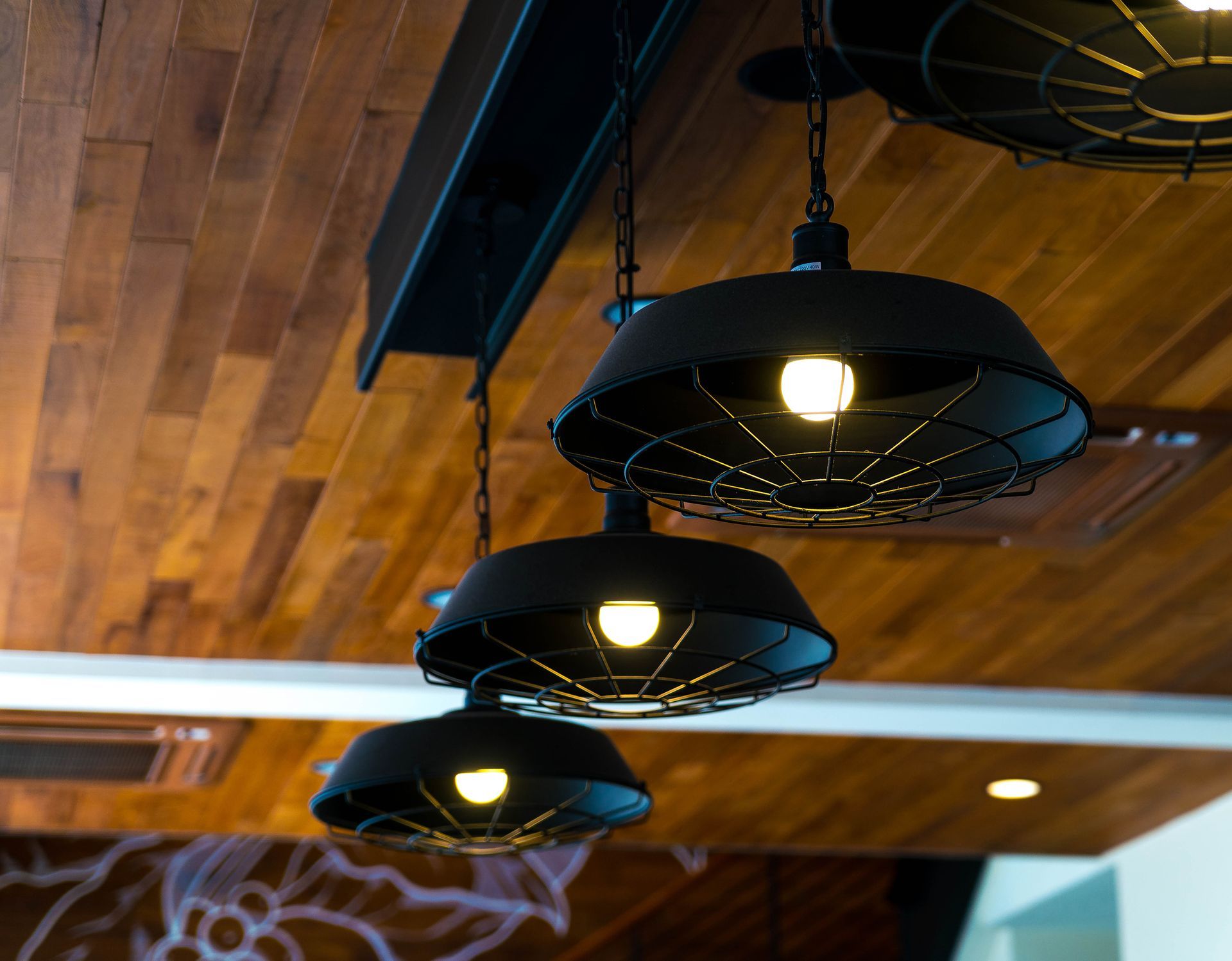 Three black pendant lights hanging from a wooden ceiling