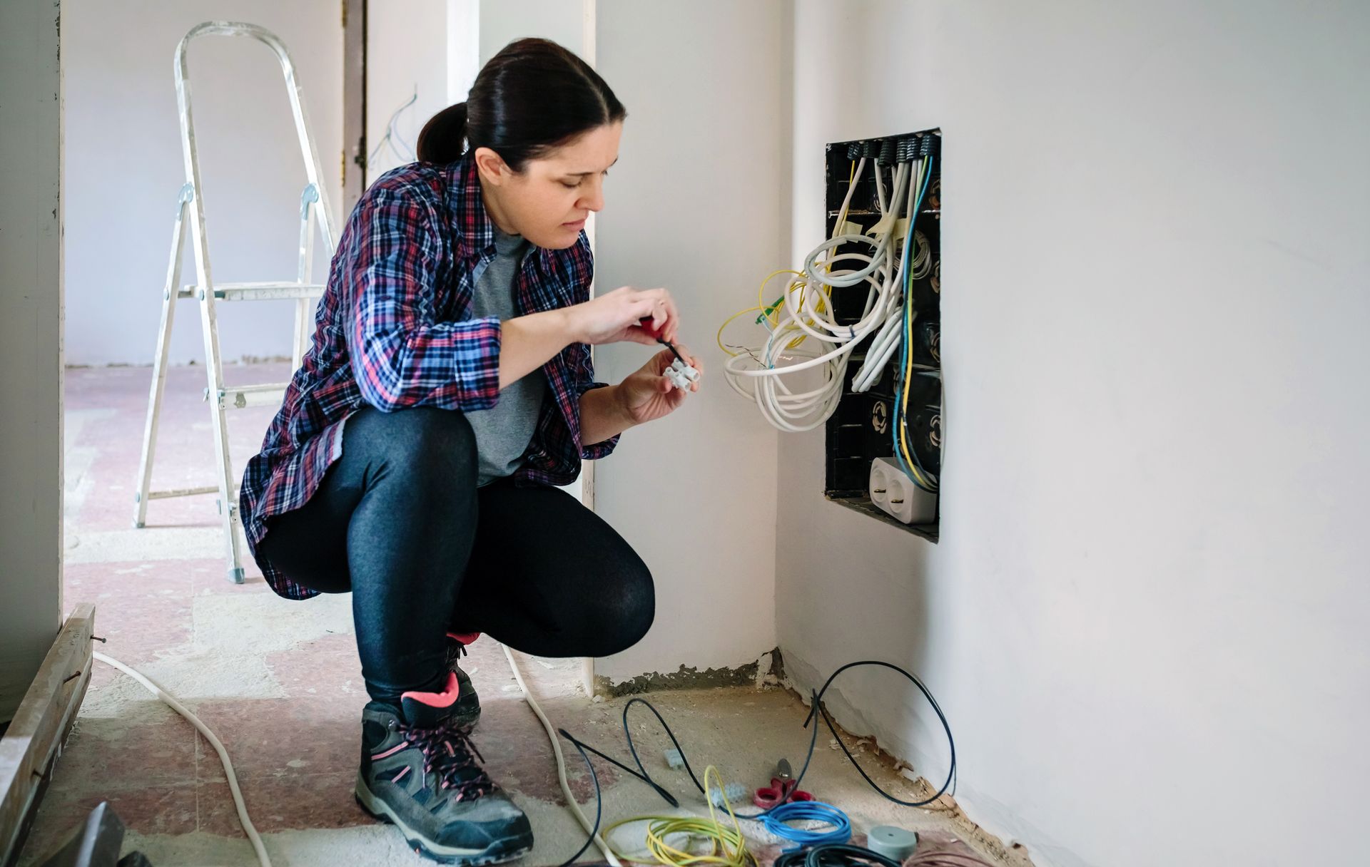 A woman is kneeling down and working on a wall.