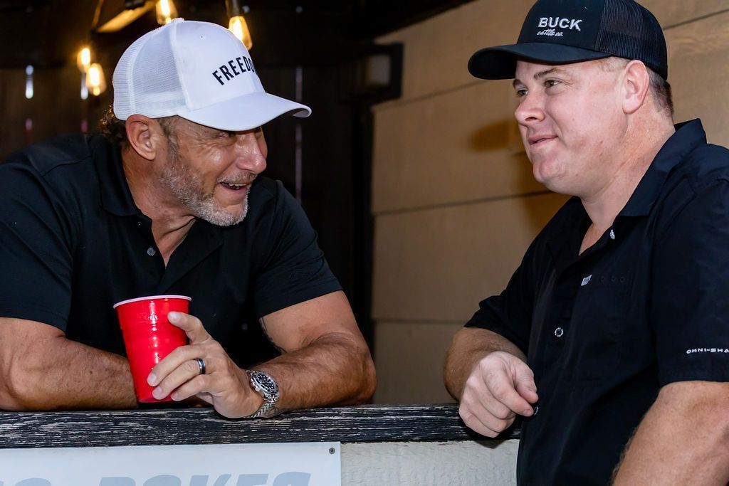 Two men talking; one in a white hat with