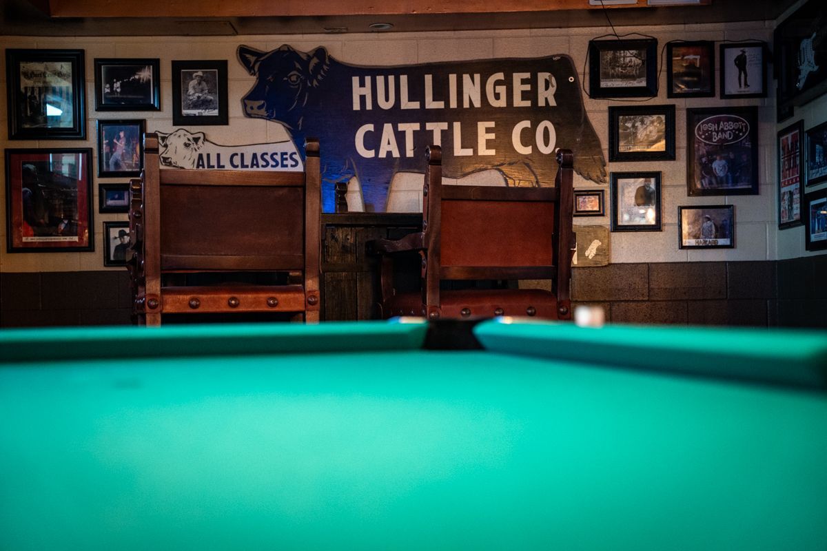 Pool table with chairs behind it, a sign saying