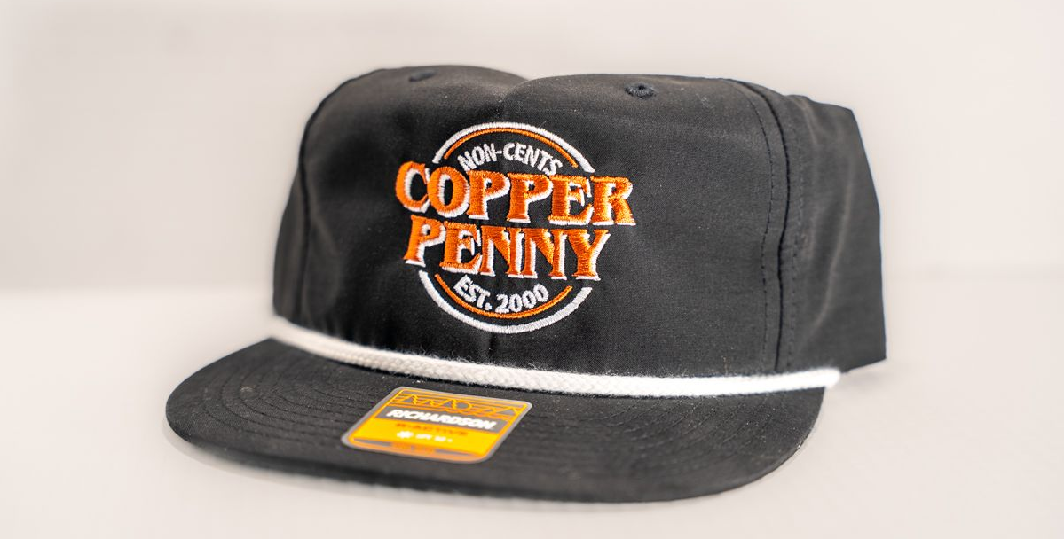 Black baseball cap with white rope and orange "Copper Penny" logo.