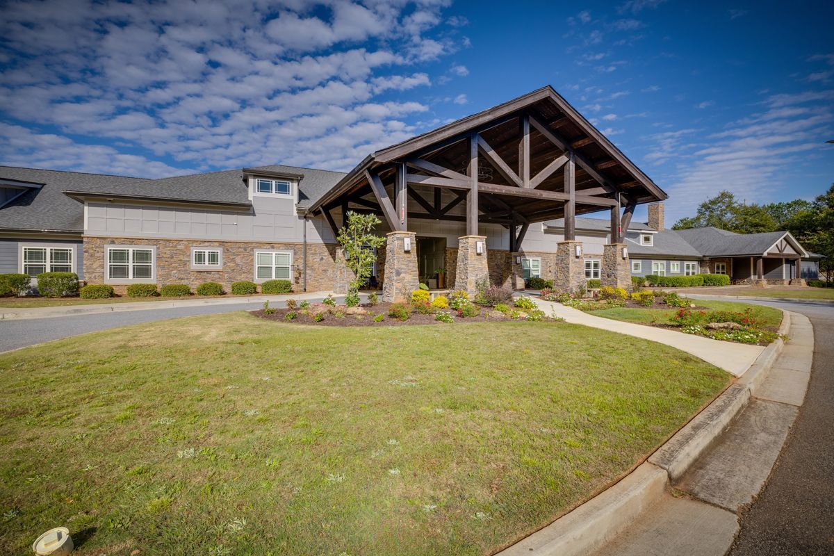 A large brick building with a wooden roof is sitting on top of a lush green lawn.