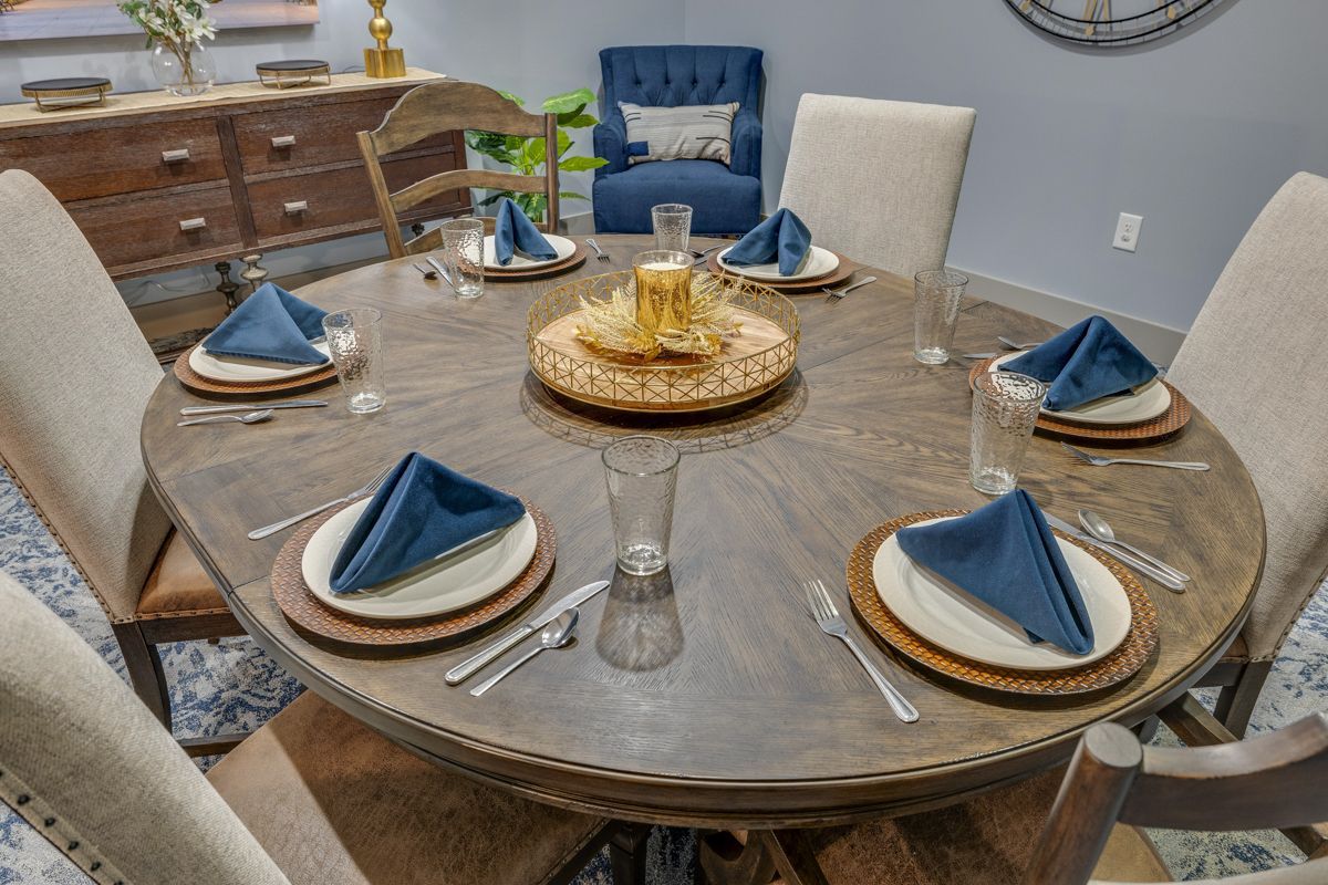 A dining room table with plates , napkins , glasses and silverware.
