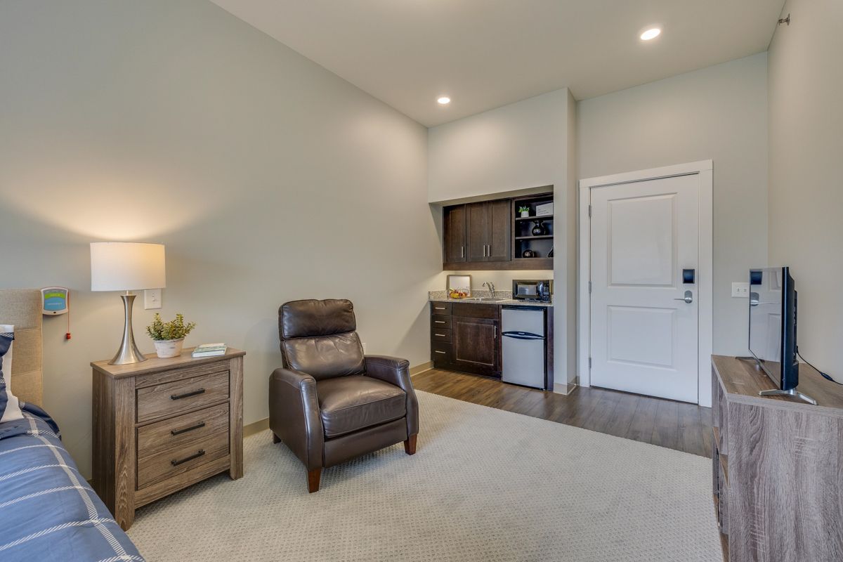 A living room with a chair , dresser , and television.