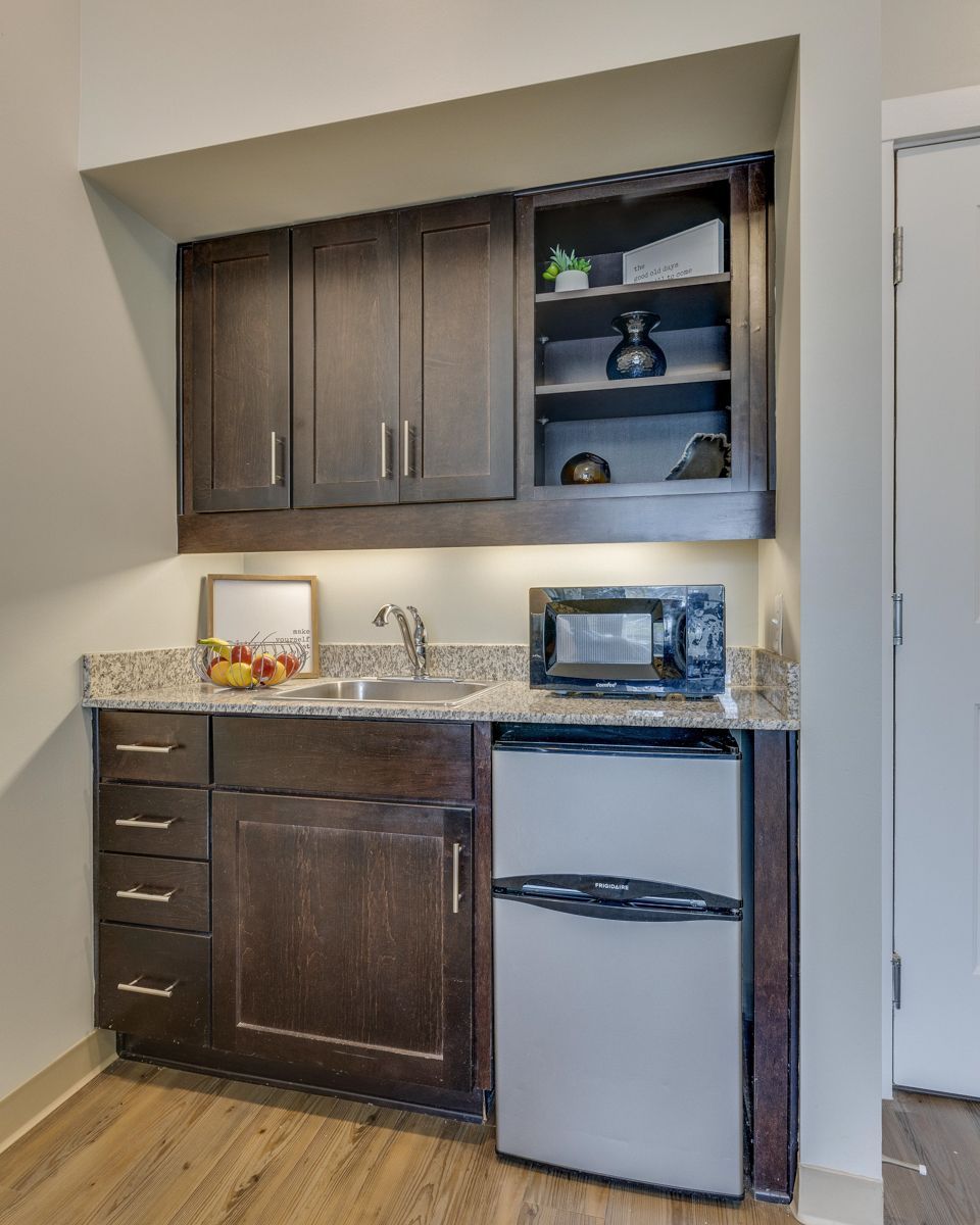 A kitchen with a sink , refrigerator and microwave