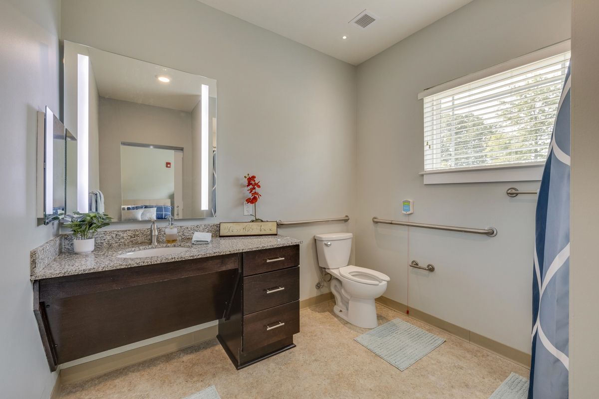 A bathroom with a toilet , sink and mirror.