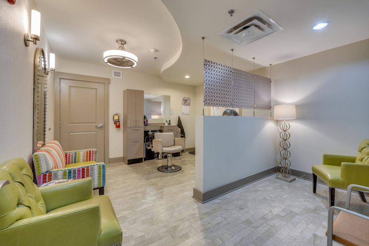 A waiting room with green chairs and a colorful chair in a salon.