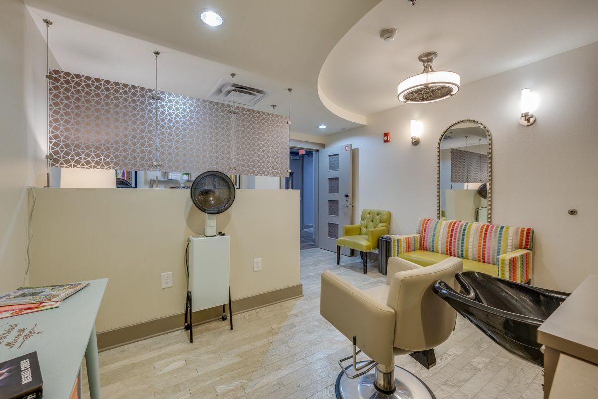 A salon with a chair , couch , and mirror.