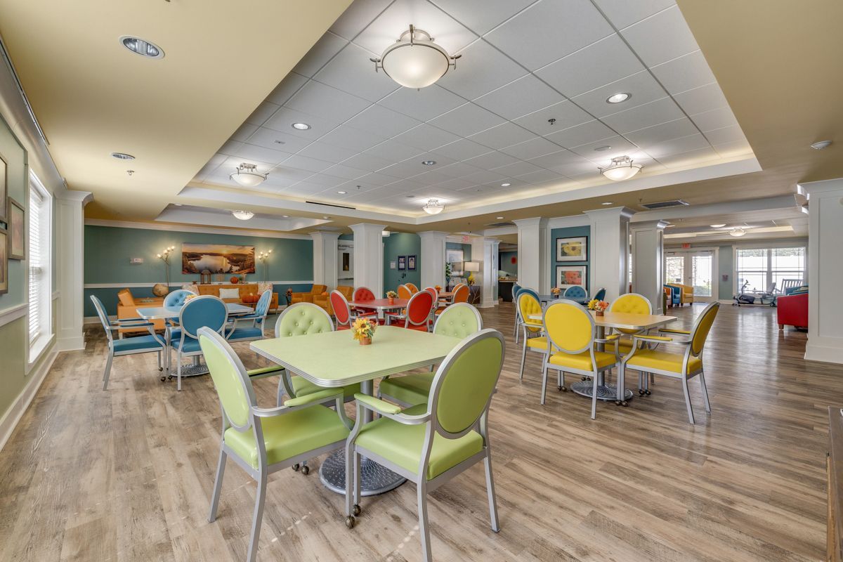 A large dining room with tables and chairs in a nursing home.
