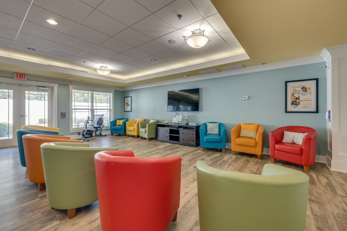 A living room filled with colorful chairs and a television.