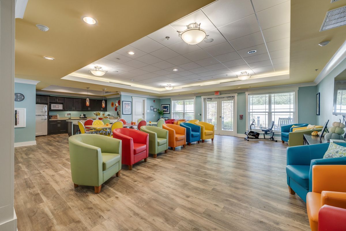 A large room filled with colorful chairs and a kitchen.