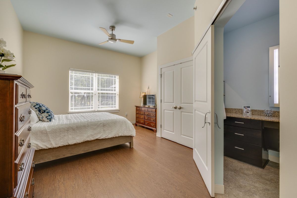 A bedroom with a bed , dresser , ceiling fan and a bathroom.