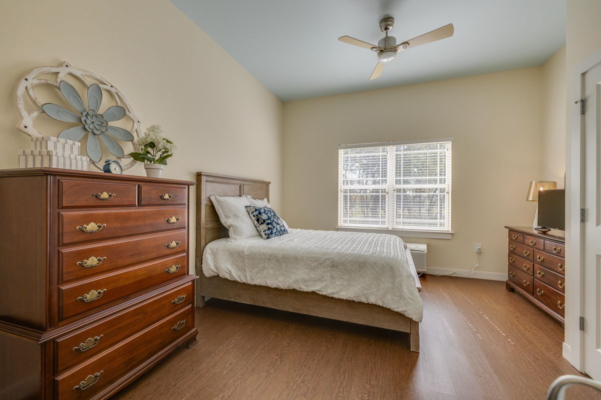 A bedroom with a bed , dresser , and ceiling fan.