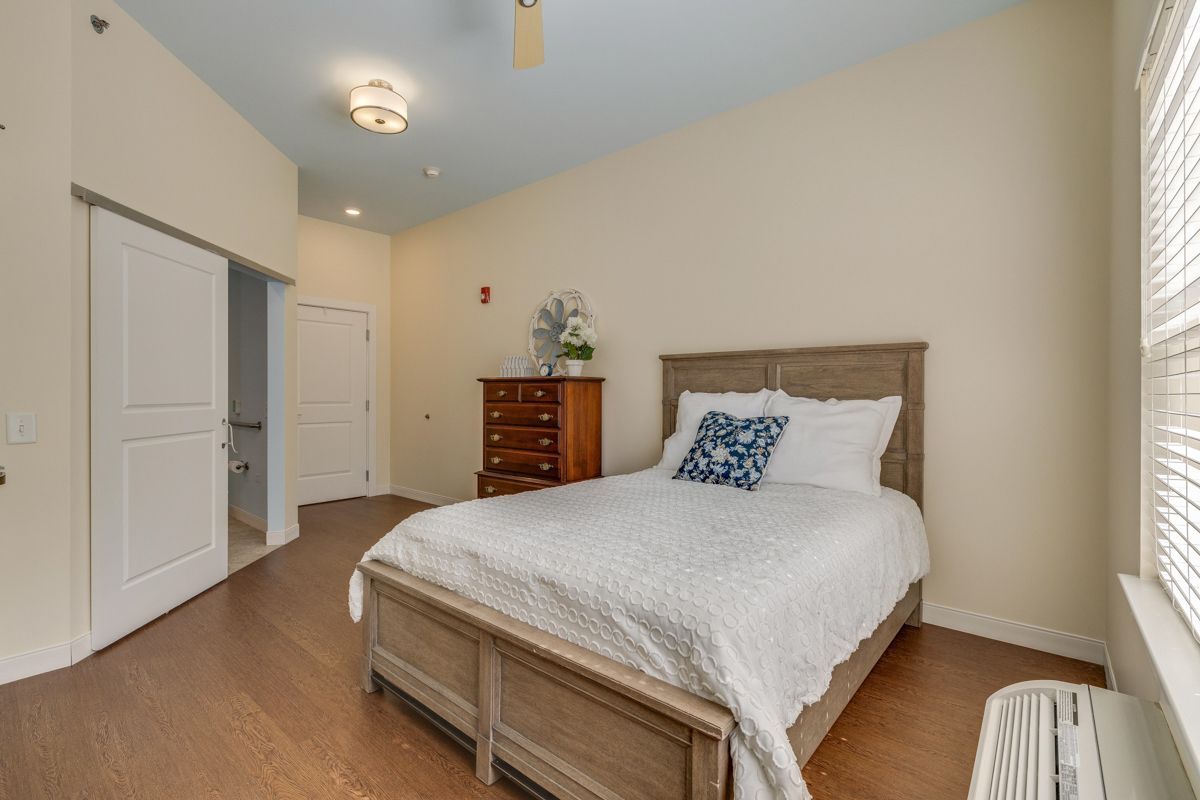 A bedroom with a bed , dresser , and window.