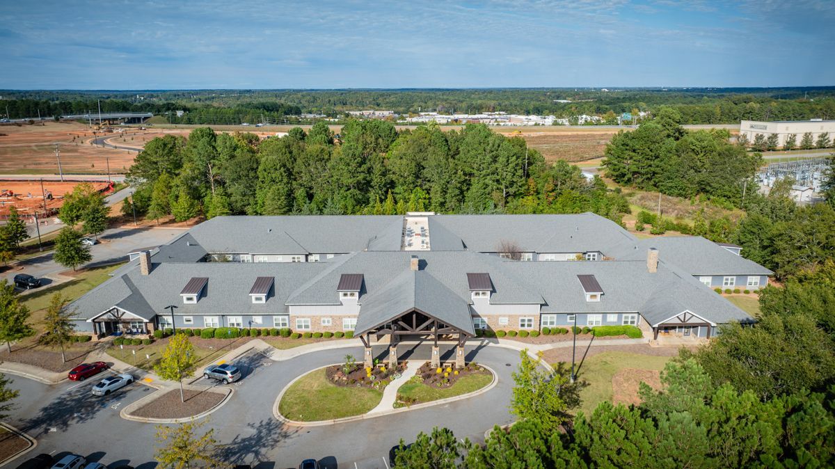 An aerial view of a large building surrounded by trees and a parking lot.