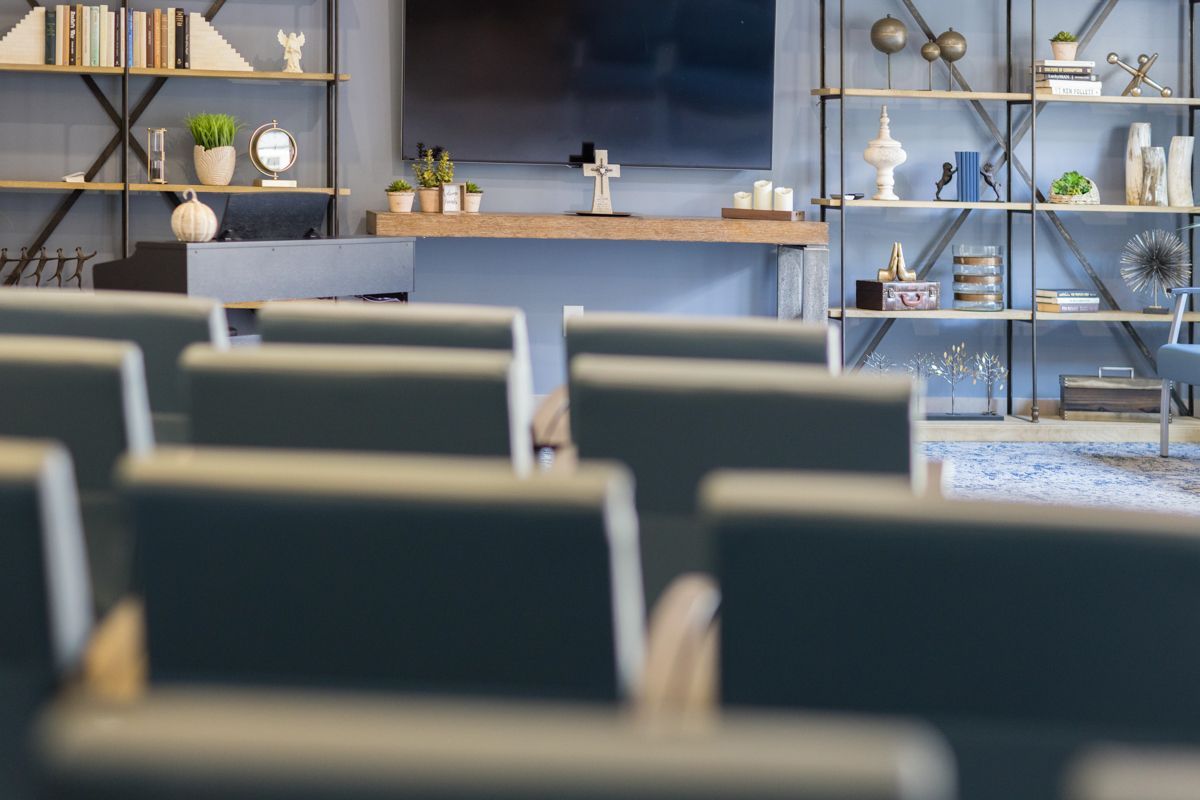 A row of chairs in a room with a television on the wall.
