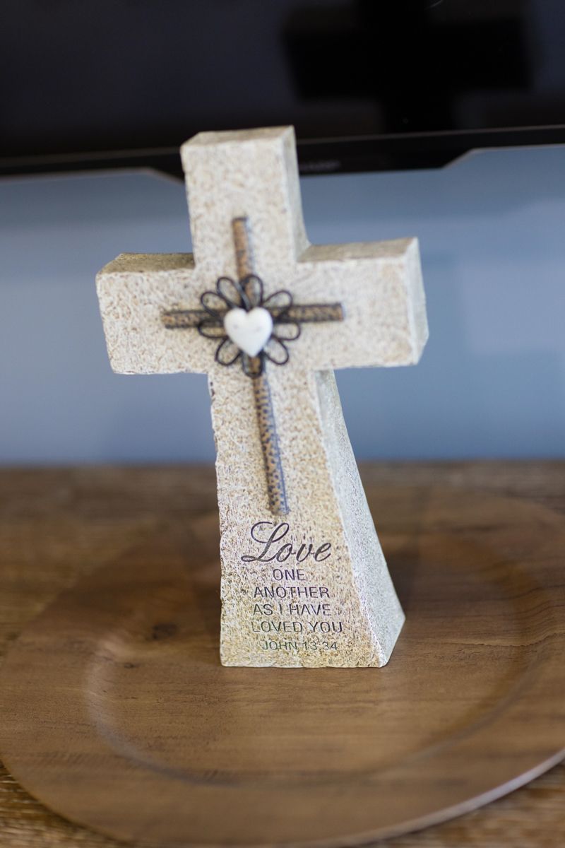 A cross is sitting on a wooden table in front of a television.