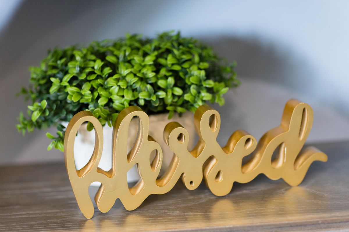 A wooden sign that says blessed is on a table next to a potted plant.