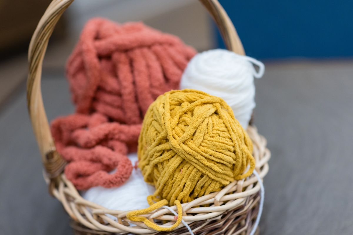 Three balls of yarn are in a wicker basket.