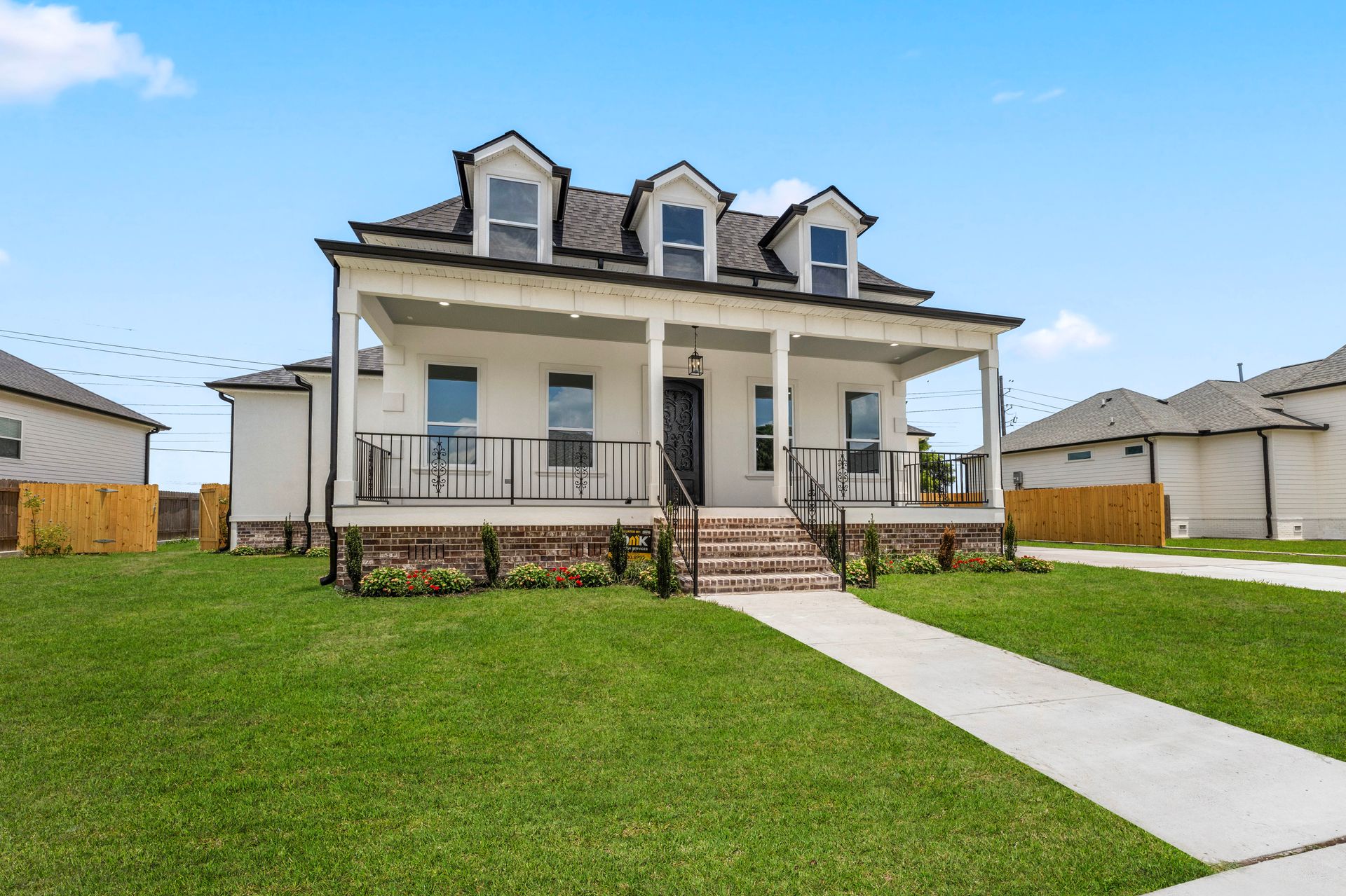 A large white house with a porch and stairs in a residential area.