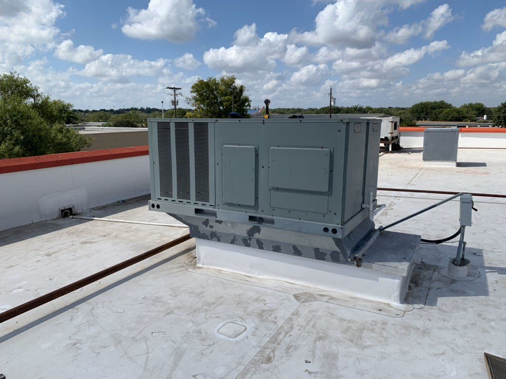 A large gray box is sitting on top of a white roof.