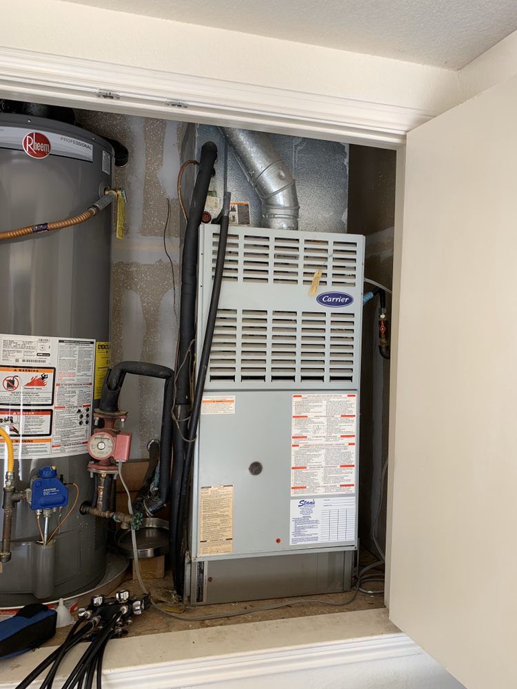 An air conditioner is sitting inside of a closet next to a water heater.