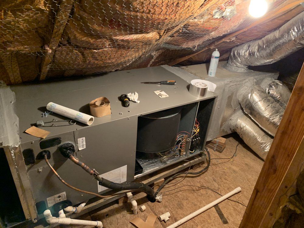 An air conditioner is being installed in an attic.