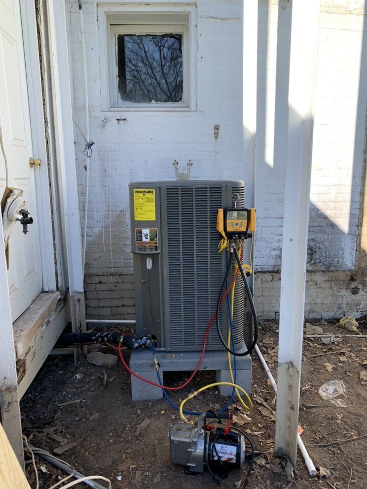 An air conditioner is being installed on the side of a house.