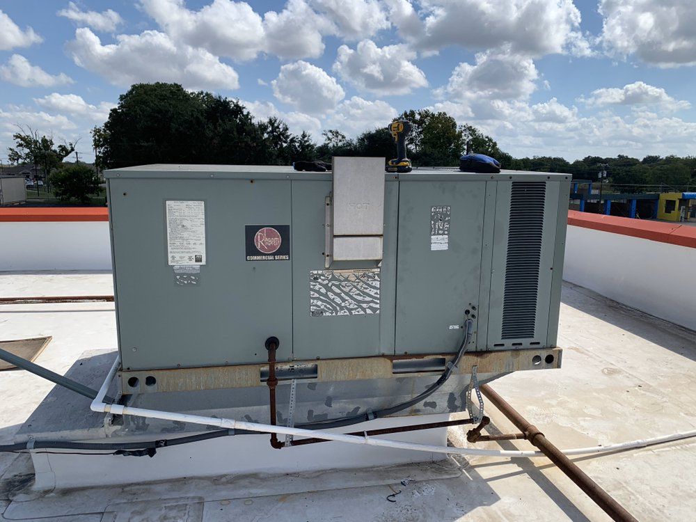 An air conditioner is sitting on top of a white roof.