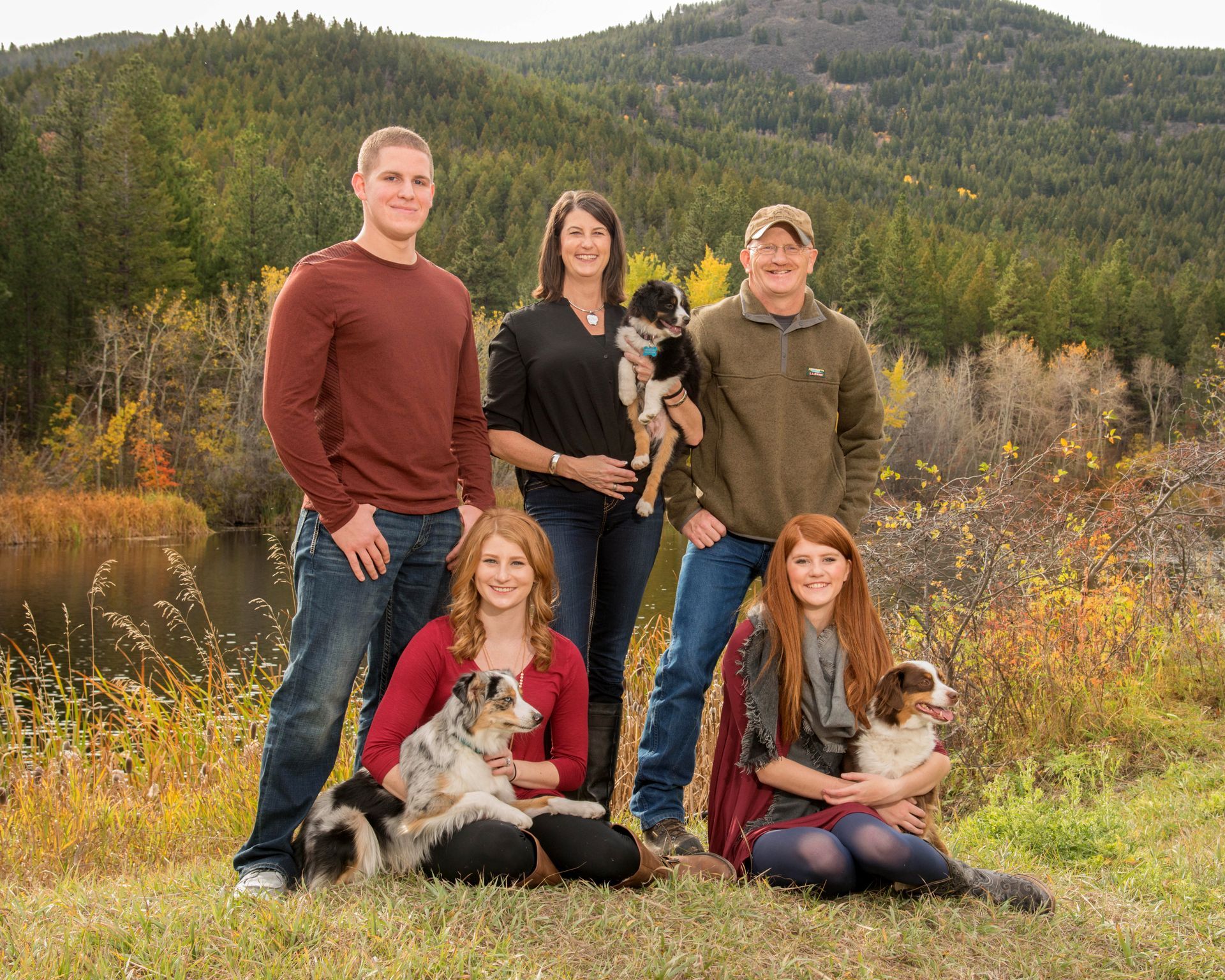 A family is posing for a picture with their dogs in a field.