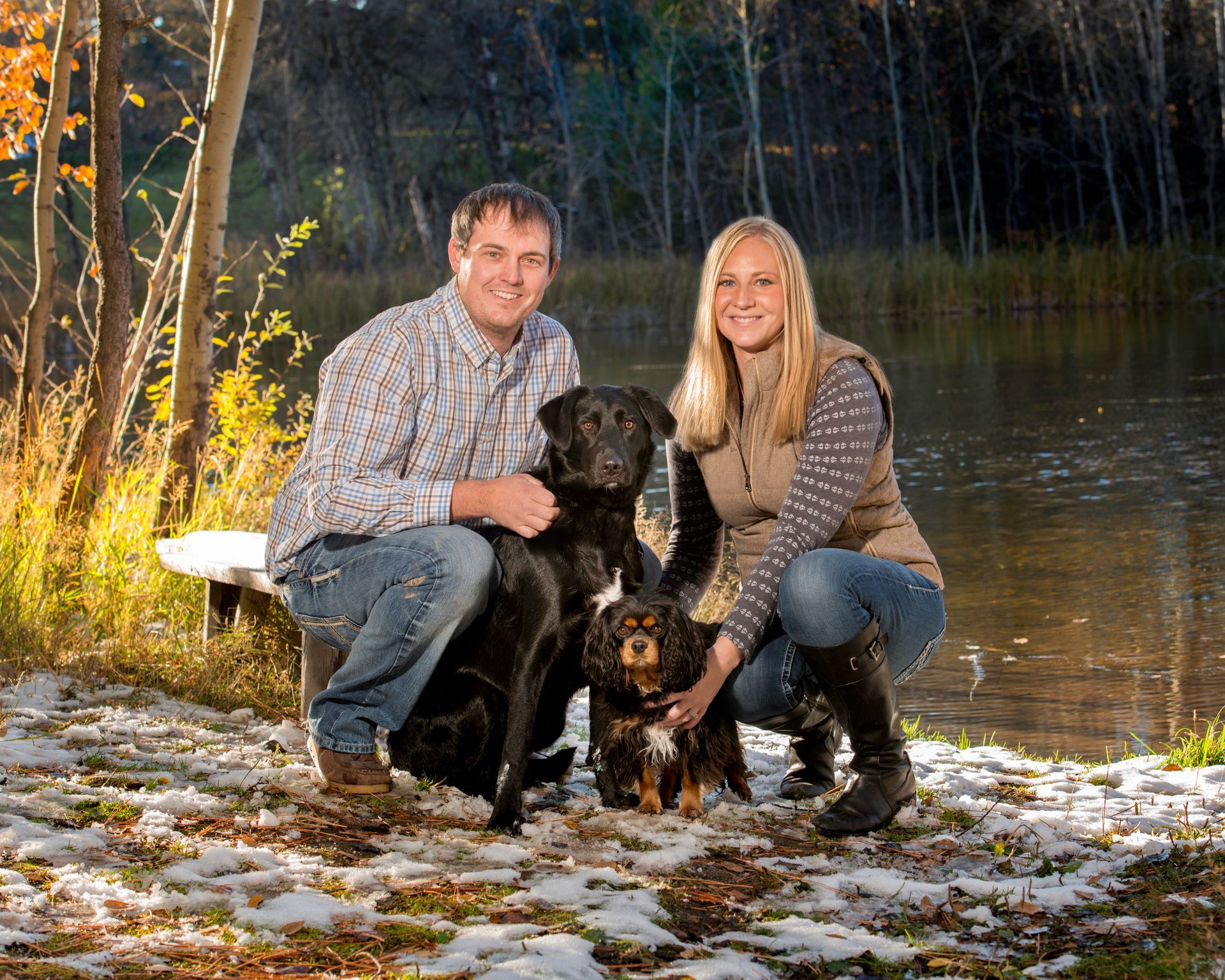 A man and a woman are posing for a picture with their dogs.