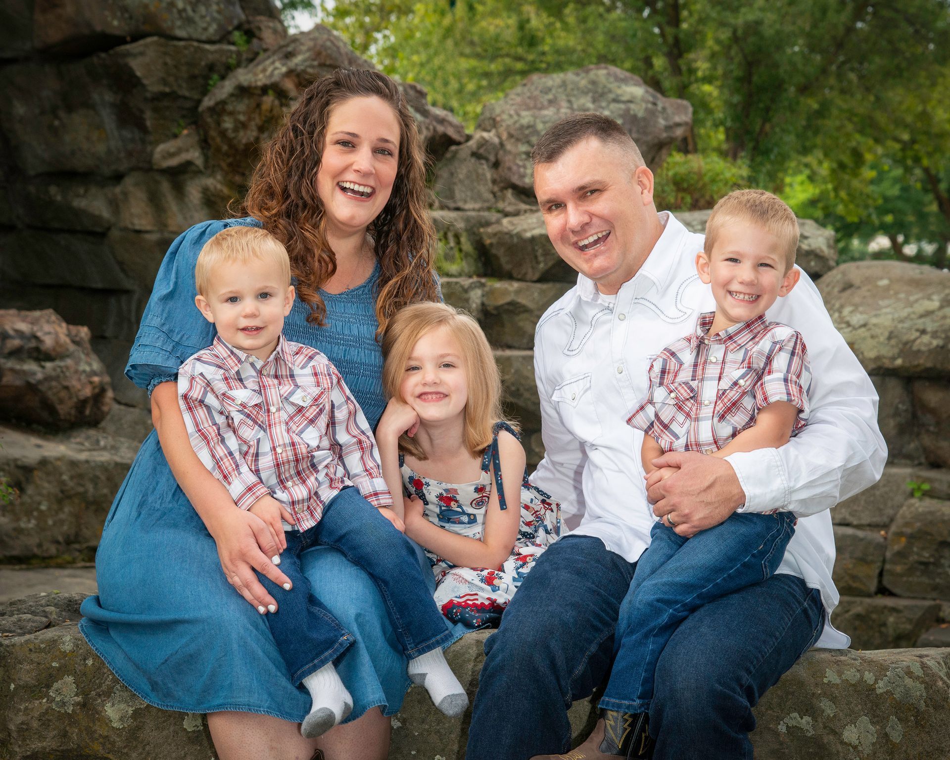 A family is posing for a picture while sitting on a rock.
