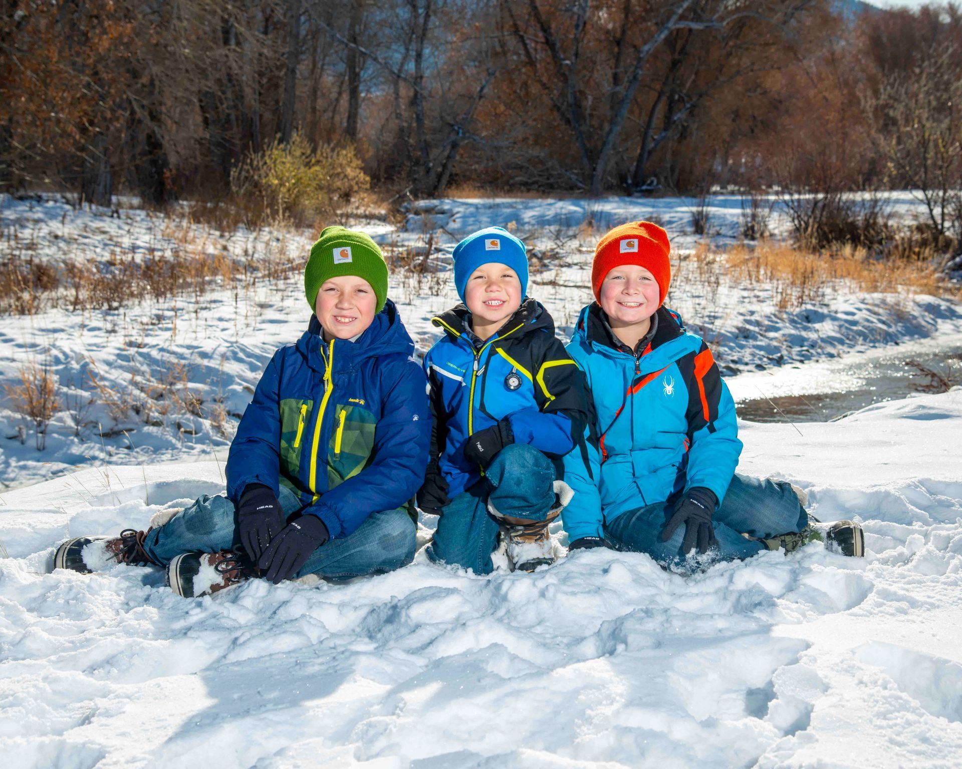 A family is sitting in the snow posing for a picture.