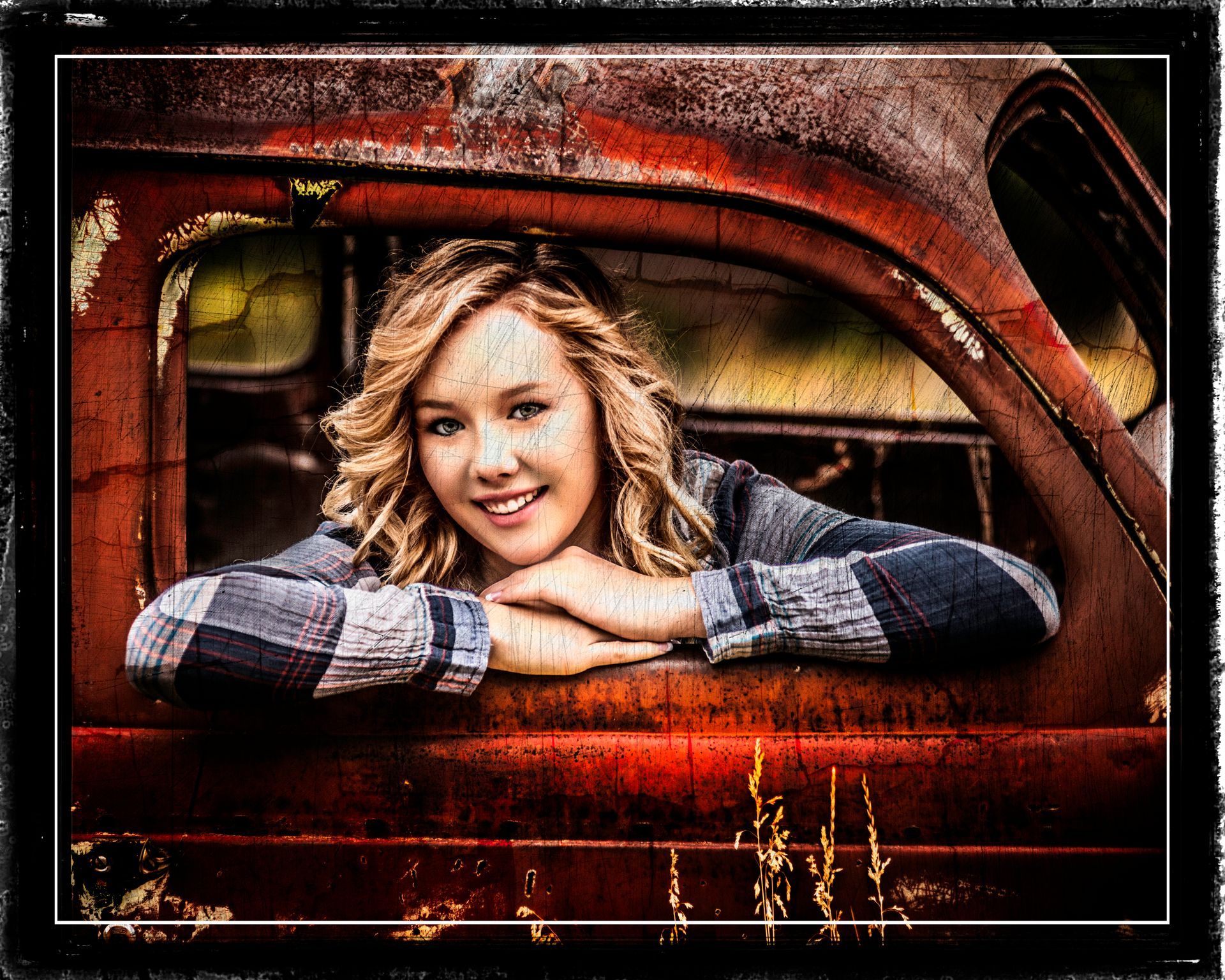 A young woman is leaning out of the window of an old rusty truck.