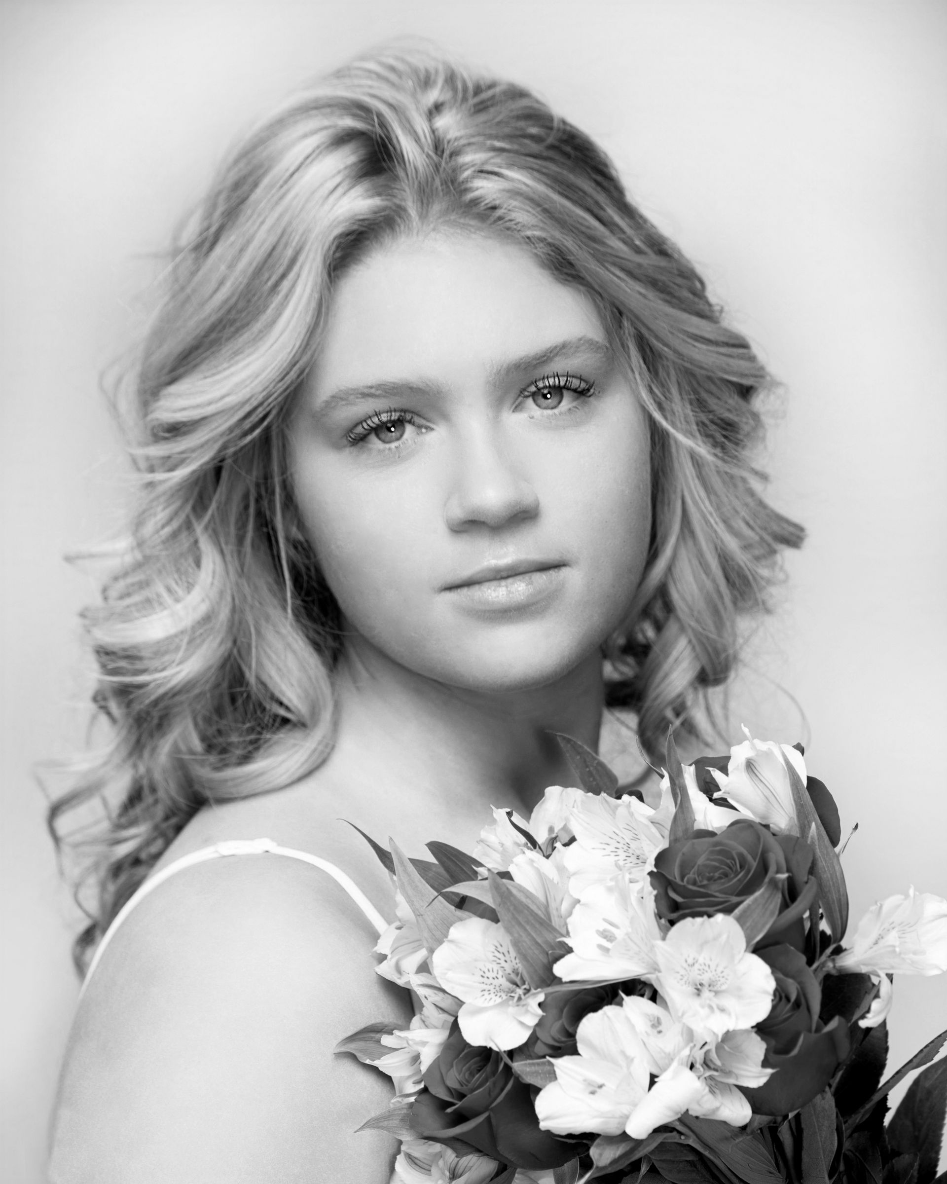 A woman is holding a bouquet of flowers in a black and white photo.