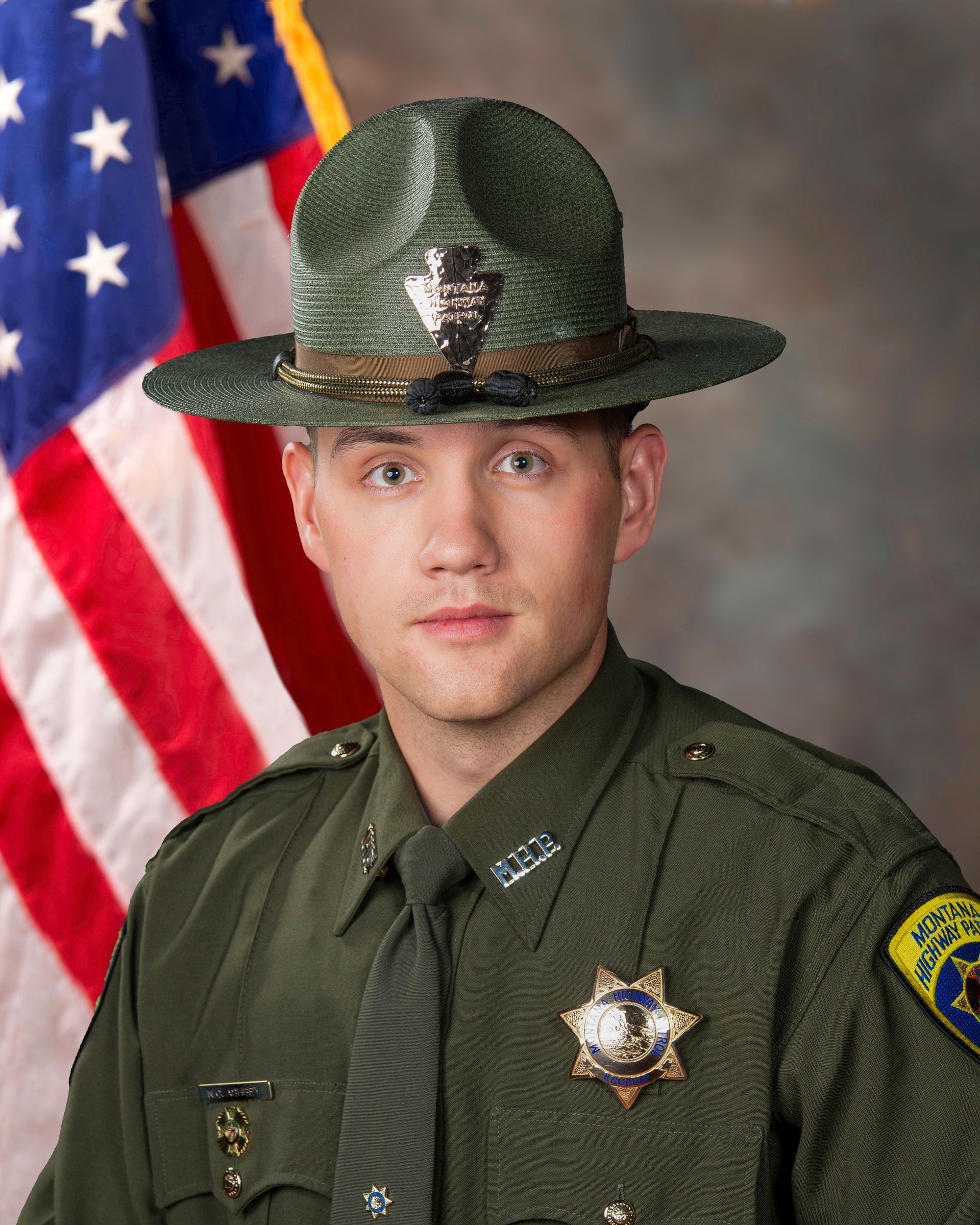A man in a sheriff 's uniform is standing in front of an american flag.