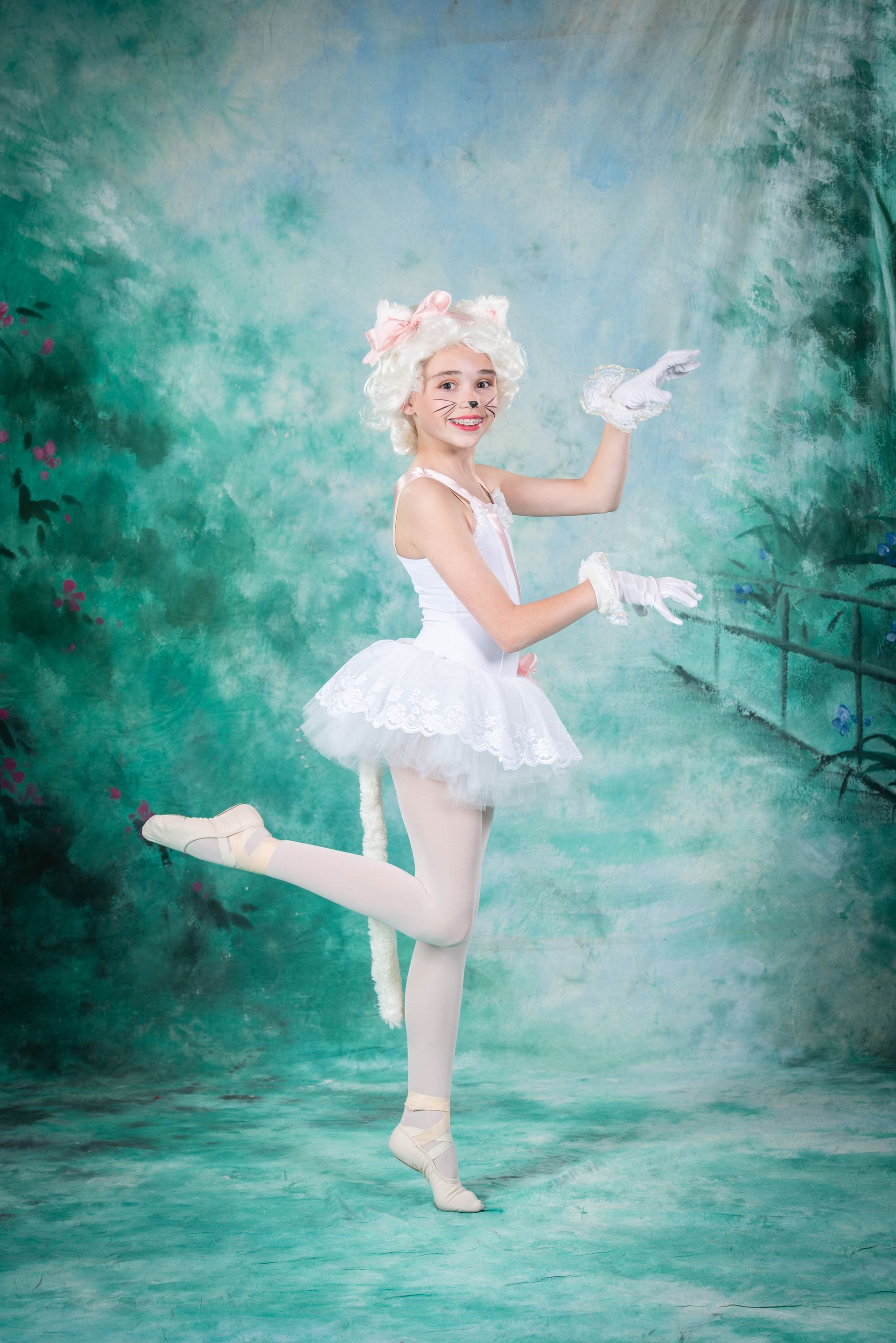 A young girl is dressed as a cat in a white tutu.
