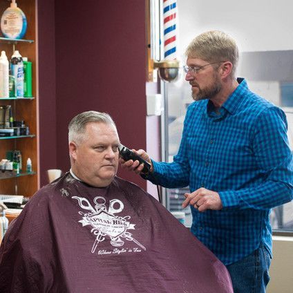 A man is getting his hair cut by a barber in a barber shop.