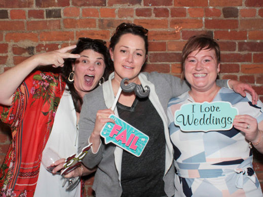 Three women are posing for a picture in front of a brick wall.