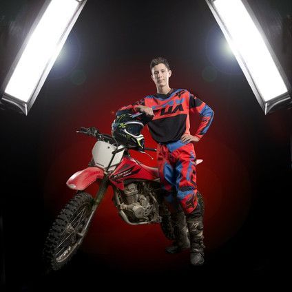 A man is standing next to a dirt bike in a dark room.