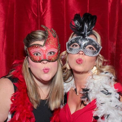 Two women wearing masks and feathers are posing for a picture