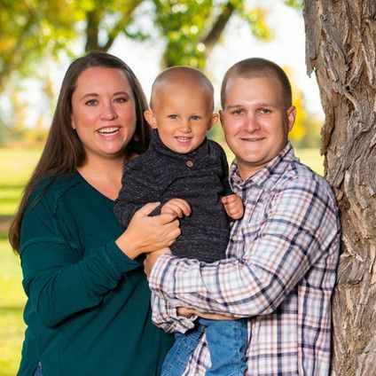 A family is posing for a picture in front of a tree.