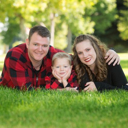 A family is posing for a picture while laying in the grass.