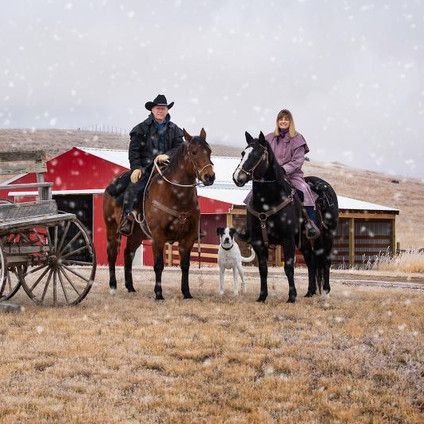 A man and a woman are riding horses in the snow.