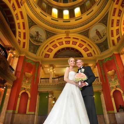 A bride and groom are posing for a picture in a large building.