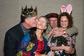 A man is kissing a woman on the cheek while wearing a crown.