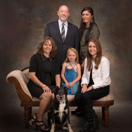 A family is posing for a picture with a dog.