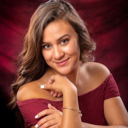 The woman is wearing a red off the shoulder top and a bracelet.